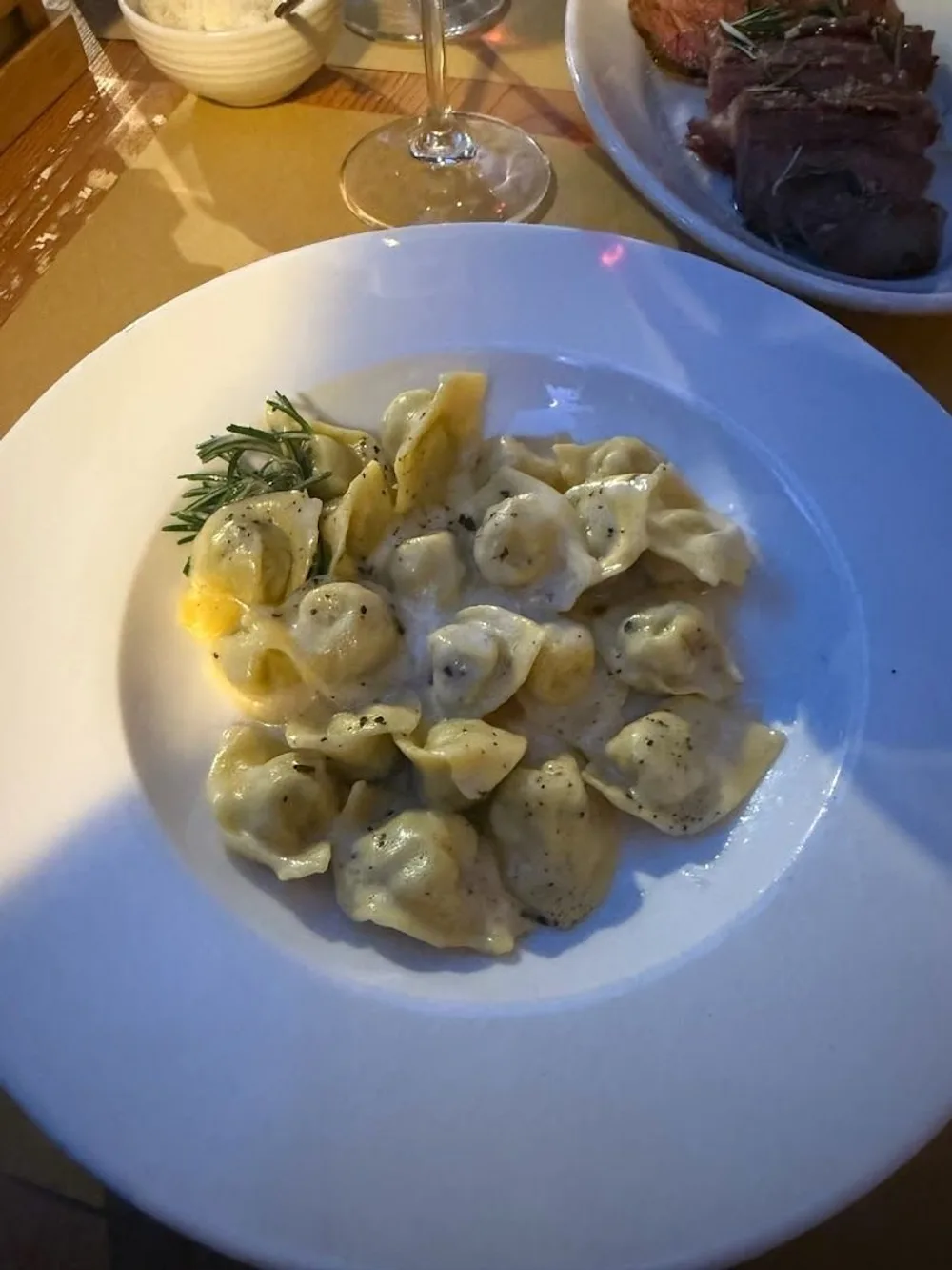 Cappellacci al burro e rosmarino in un piatto bianco Cappellacci al burro e rosmarino in un piatto bianco